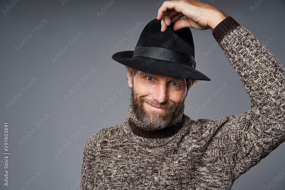 Smiling mature man in warm sweater lifting his hat greeting Smiling mature man in warm sweater lifting his hat greeting