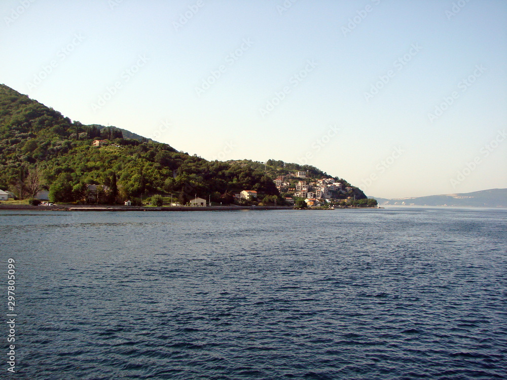 Panorama from the deck of a ship of Croatian settlements on the Adriatic coast against a background of hills covered with forest.