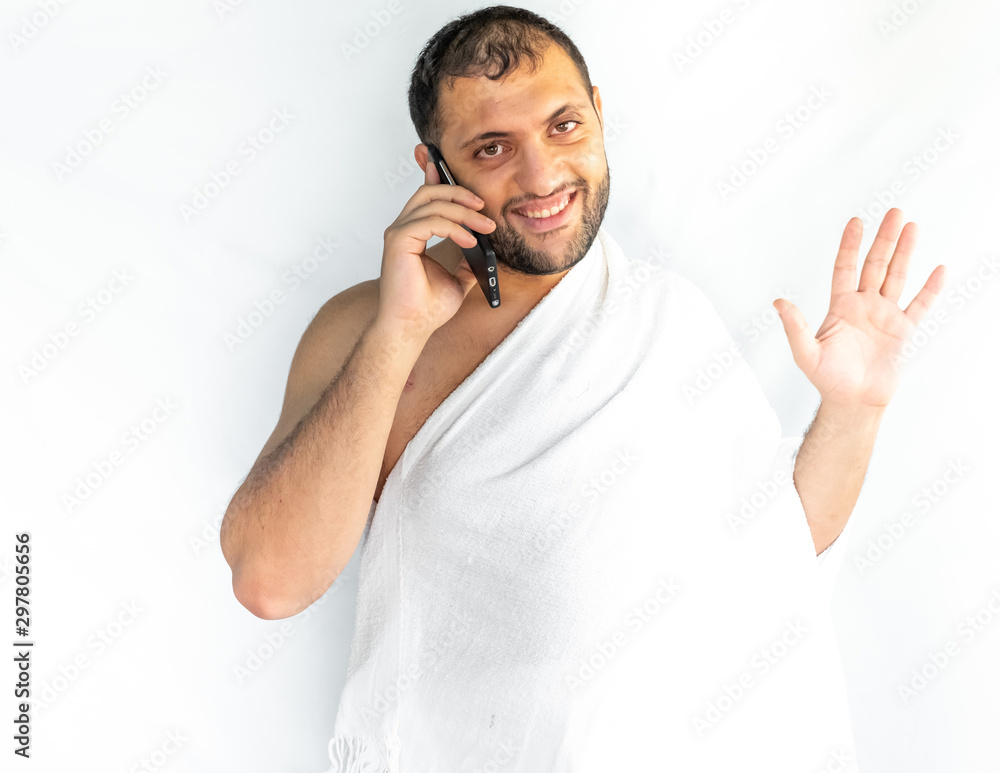 Muslim man making a phone call while wearing pilgrimage clothes Muslim man making a phone call while wearing pilgrimage clothes