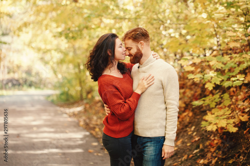 Portrait of beautiful couple man woman in love. Boyfriend and girlfriend hugging kissing outdoor in park road on autumn fall day. Togetherness and happiness. Authentic real people feelings.