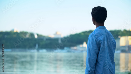 African american guy resting on river embankment enjoying city view, landscape