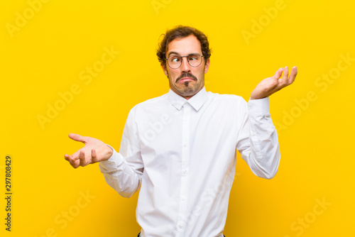 Schilderij op canvas young handsome man shrugging with a dumb, crazy, confused, puzzled expression, f