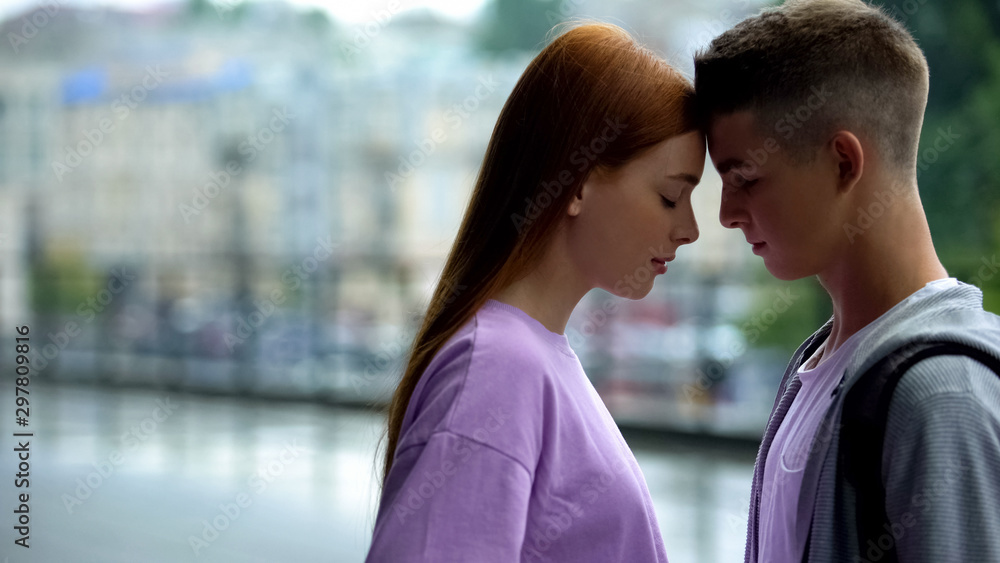 Young couple looking each other on rain city background touching foreheads