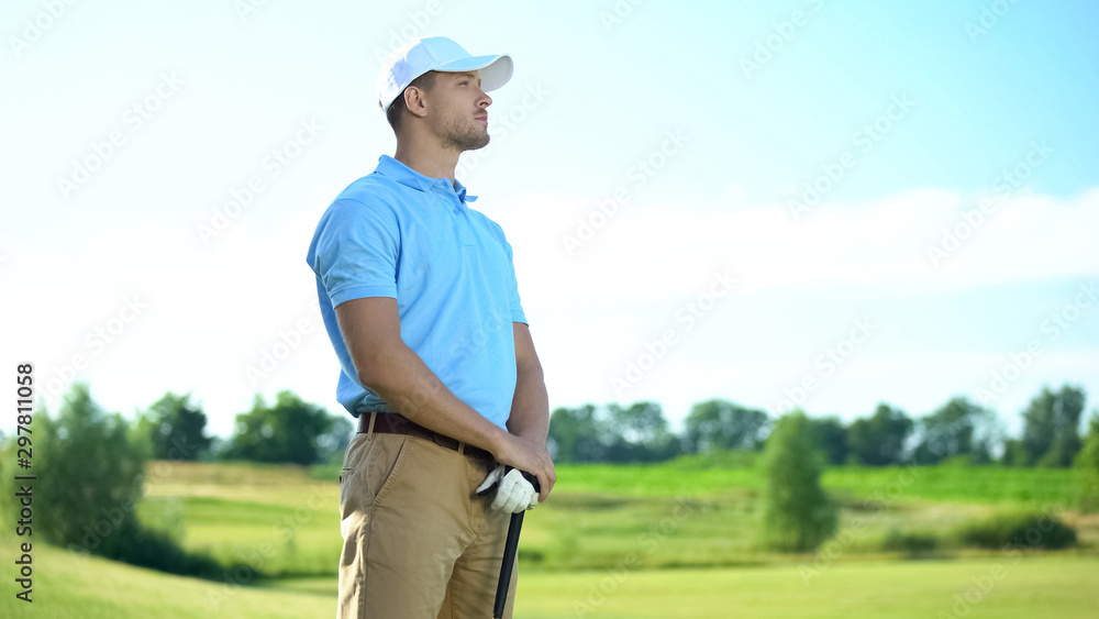 Inexperienced golf player with club in hands upset with failed shot, loser