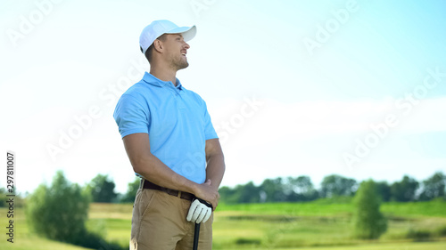 Smiling golfer pleased with successful shot at course, club-and-ball sport