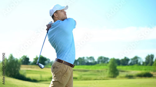 Experienced male golf player taking swing and hitting ball, professional golfer
