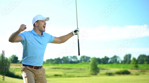 Beginner golf player with club in hand rejoicing successful shot, luck and sport