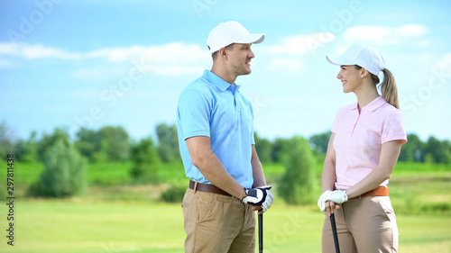 Female and male golf player with club smiling each other, flirt and training