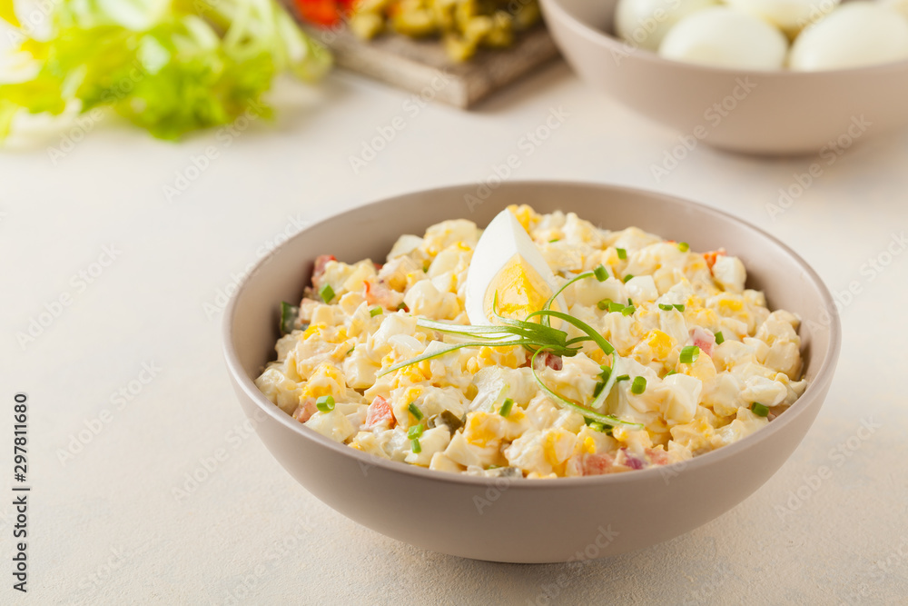 A light egg salad with celery, gherkin, pepper and mayonnaise. Served in a bowl on a light background. Front view. A light egg salad with celery, gherkin, pepper and mayonnaise. Served in a bowl on a light background. Front view.