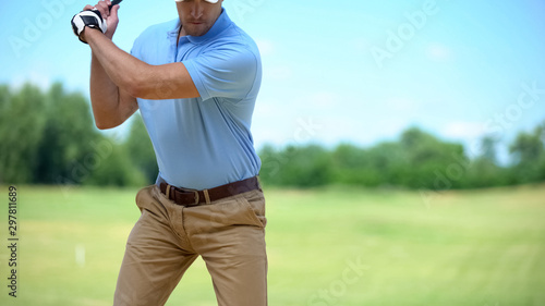 Serious golfer hitting ball in backswing position, preparing for competition