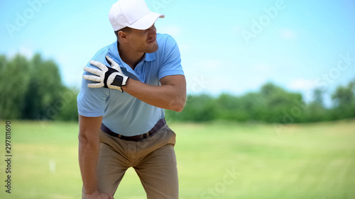 Fotografie Young male golf player suffering terrible shoulder spasm after shot, trauma