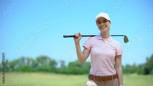 Beautiful woman golf player with club smiling on camera, favorite hobby, lessons