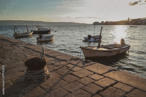 Sunset landscape scene in small sea town. Fisherman ships,sea and stone road.