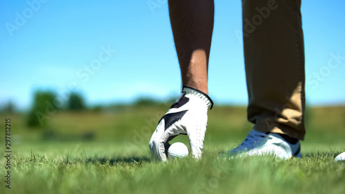Male golfer teeing off golf ball before swing, professional and luxury sport