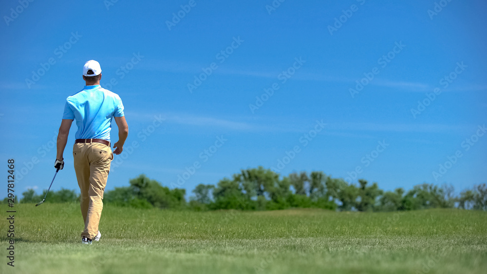 Athletic man with iron club walking on course, sport and training, elite hobby Athletic man with iron club walking on course, sport and training, elite hobby