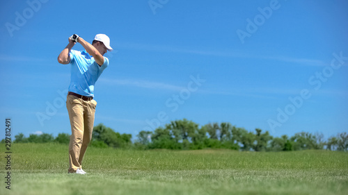Professional golf player hitting swing shot at course, training before game