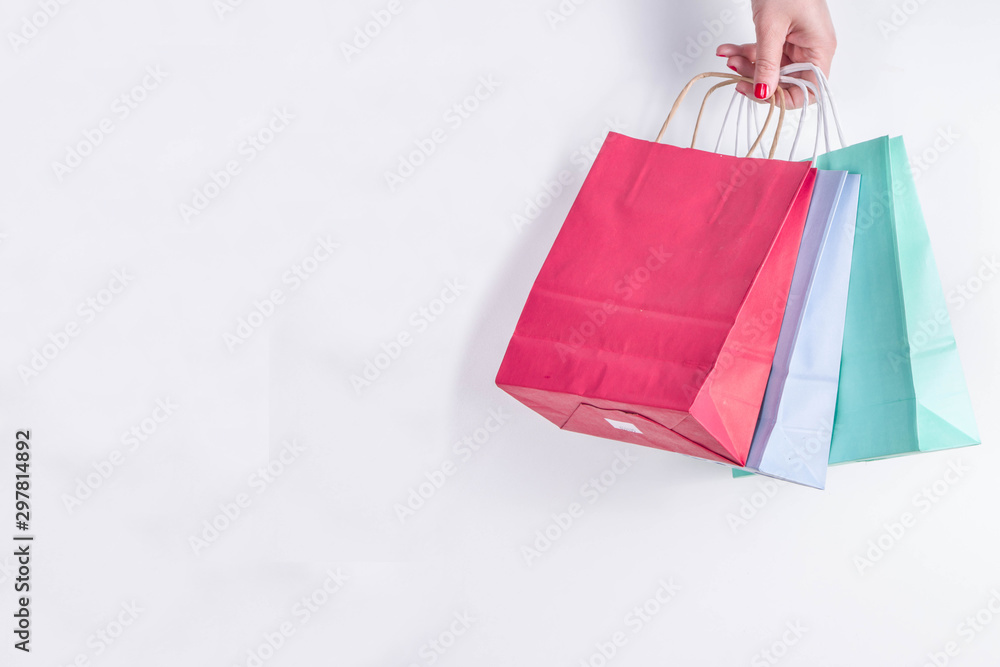 Christmas shopping and sale concept. Buying Christmas gifts. Woman hand hold pastel colored paper bags with xmas  and New Year gifts. On white background copy space