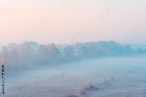 Scenic foggy autumn landscape at sunrise. Aerial view on countryside. Colorful autumnal background. Soft focus