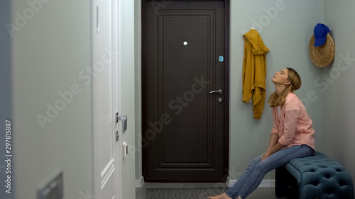 Exhausted woman sitting in hall of apartment, feeling tired after work, lonely photo