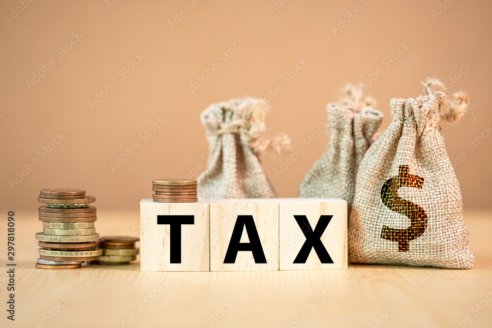 Tax wording on wooden cubes with US dollar coins and bag. - obrazy, fototapety, plakaty 