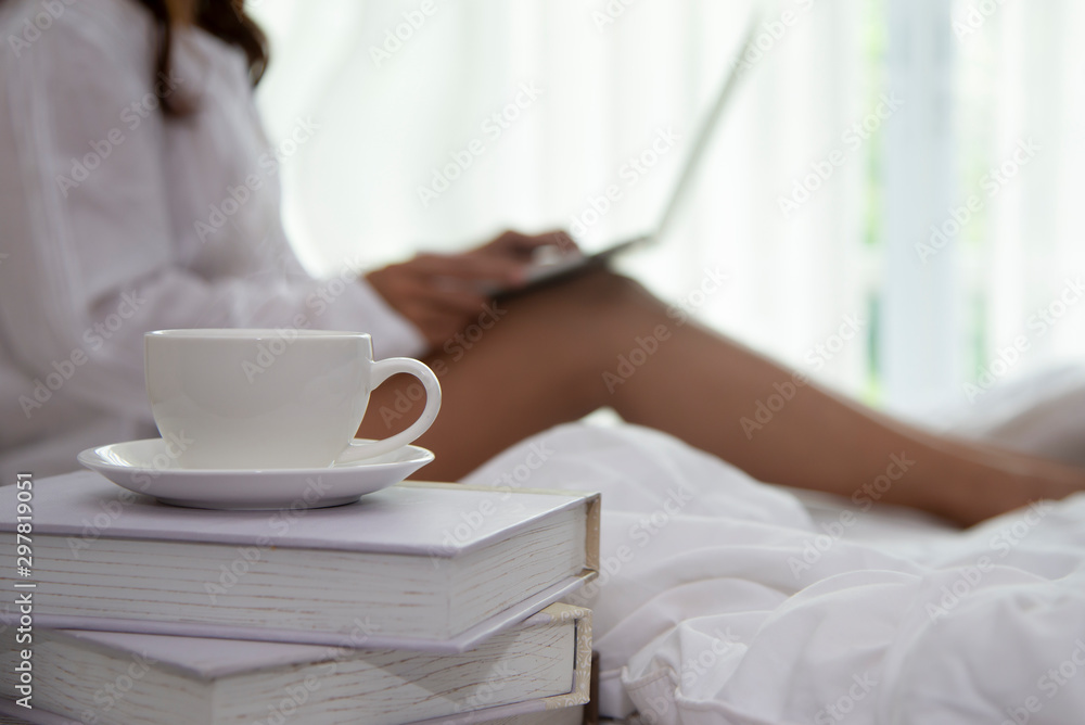 Close up on coffee cup with blurred relax woman using laptop Close up on coffee cup with blurred relax woman using laptop