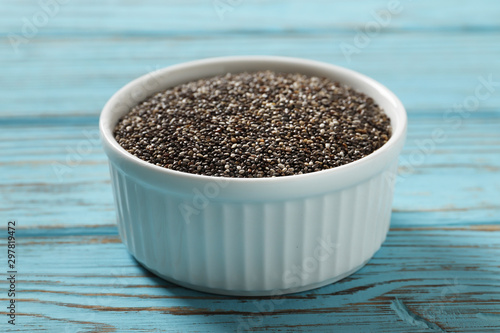 Chia in a white ceramic bowl on a blue wooden background.