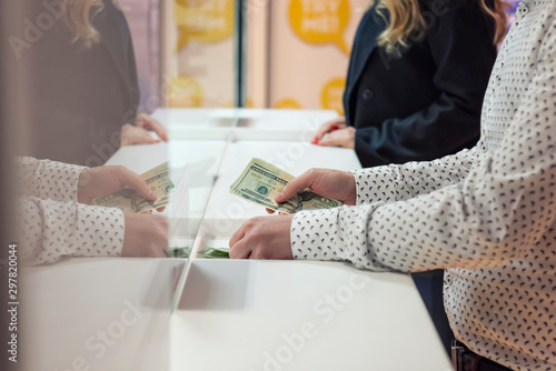 Money exchange concept / Male hand with money at cash desk. Currency exchange concept. photo