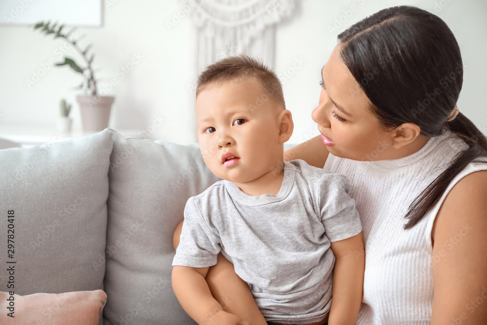 Asian mother and cute little baby sitting on sofa at home Asian mother and cute little baby sitting on sofa at home