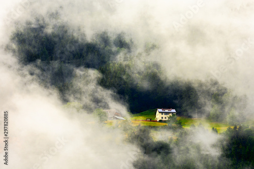 House in a high altitude european forest in a summer foggy, misty day
