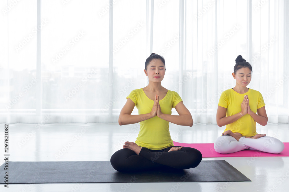 The beautiful of two Asian women are exercise yoga in the yoga room for good health and flexibility of the muscles with feel good and happiness. It is a lifestyle activity healthy for everybody.