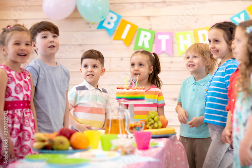 Group of kids having fun by festive table at birthday party