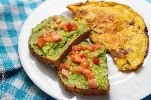 Healthy breakfast with omelette and guacamole toast on blue background