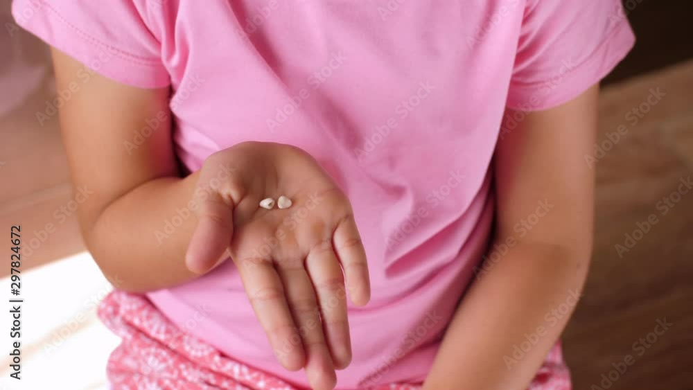 The child opens his hand with milk teeth inside. Teeth on the girl's palm. First lost milk teeth. The child opens his hand with milk teeth inside. Teeth on the girl's palm. First lost milk teeth.