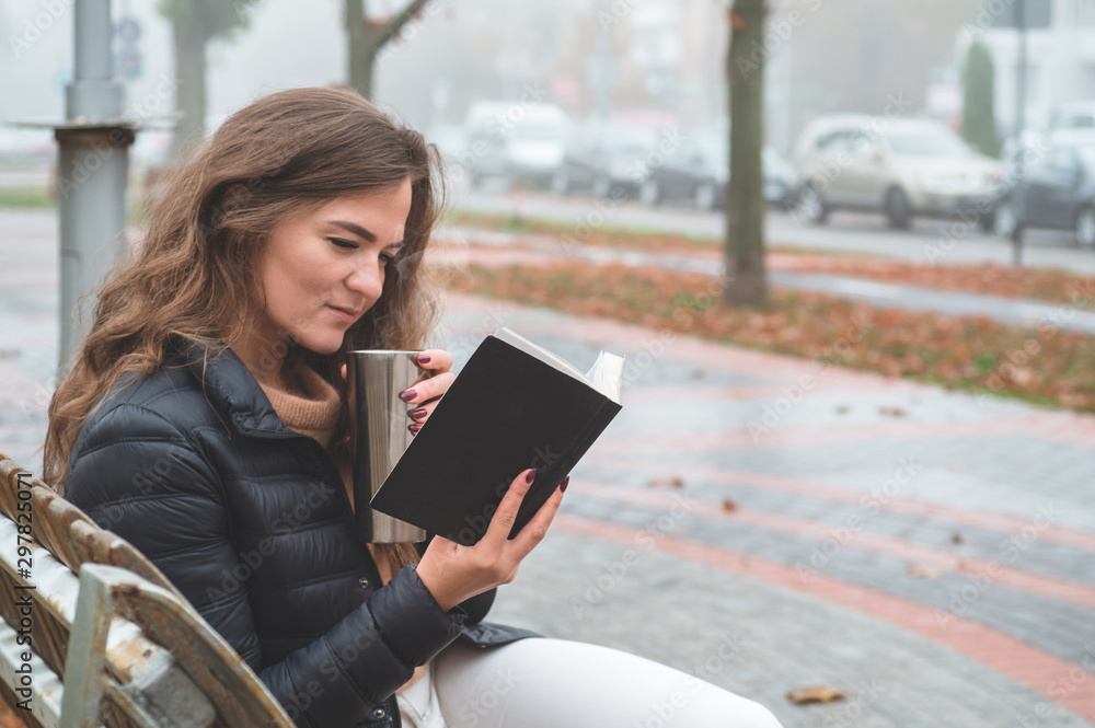 Girl holds book in her hands. The girl sitting on a bench, reading a book. Girl holds book in her hands. The girl sitting on a bench, reading a book.