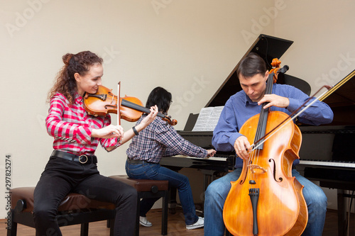 Family trio rehearsing. Father plays the cello, daughter is a violinist, mother plays the piano
