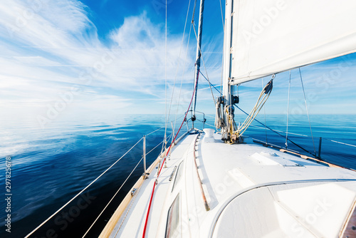 White sloop rigged yacht sailing in an open Baltic sea on a clear sunny day. A view from the deck to the bow, mast and sails. Estonia