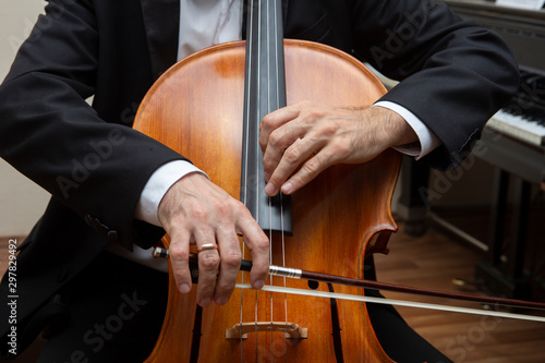 Unrecognizable cellist playing the cello. In the hands of the cellist bow.