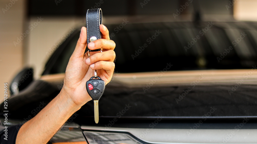 A man holding car key on black car background, journey of life concept A man holding car key on black car background, journey of life concept