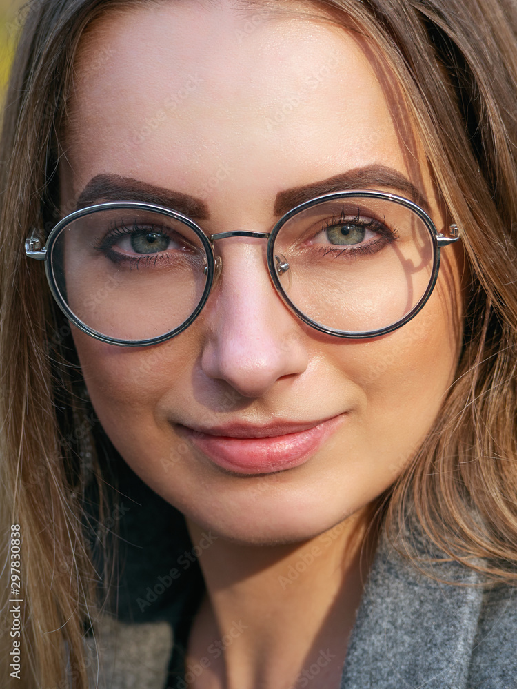 Close up street headshot portrait of young blonde haired charming smiling young woman with blue eyes looking into camera liten warm yellow evening sun Close up street headshot portrait of young blonde haired charming smiling young woman with blue eyes looking into camera liten warm yellow evening sun