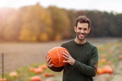 Man holding pumpkin in pumpkin patch field