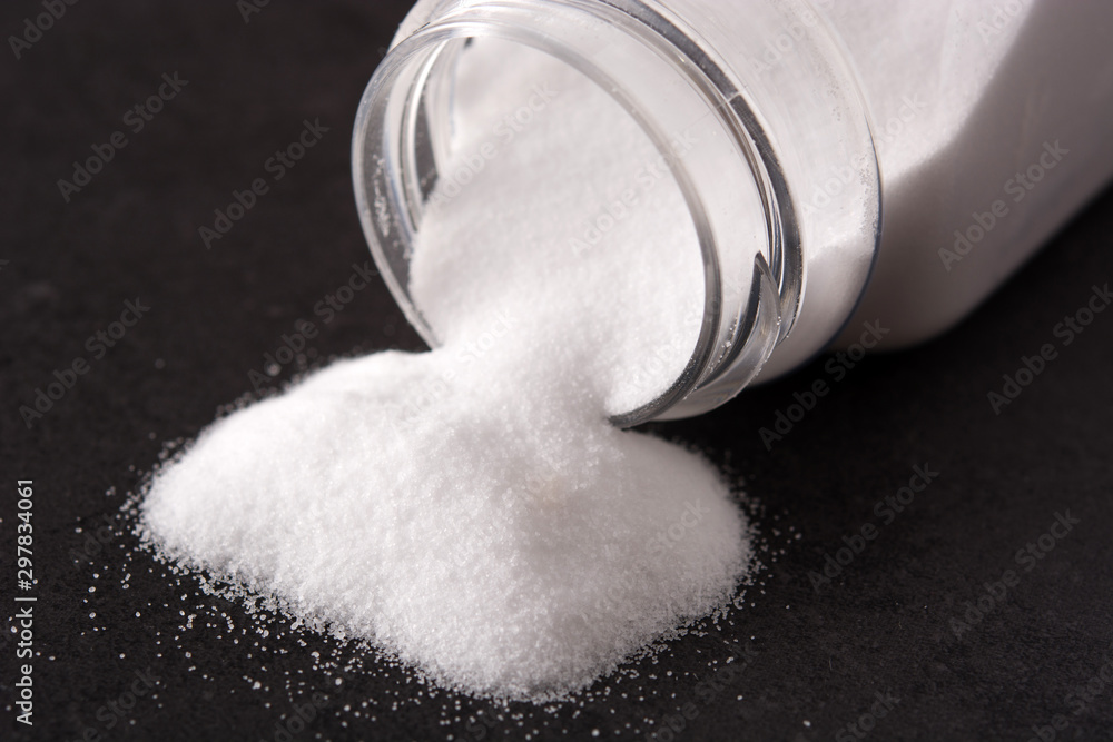 Baking soda in a poured bottle on black background Baking soda in a poured bottle on black background