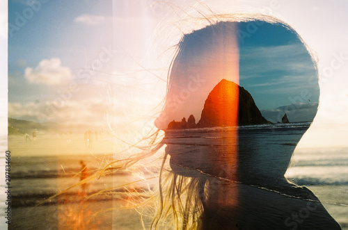 Boulders on beach reflected in woman's silhouette