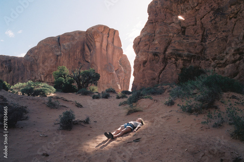 Woman lying in ray of light in desert by rock formations