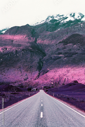 Pink and purple hues on mountains above empty road