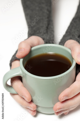 Holding green cup with tea  coffee in hands wearing mitts