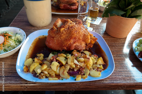 Fried pork hock on the plate with farm potatoes and salad. Everyday German food on the table.
