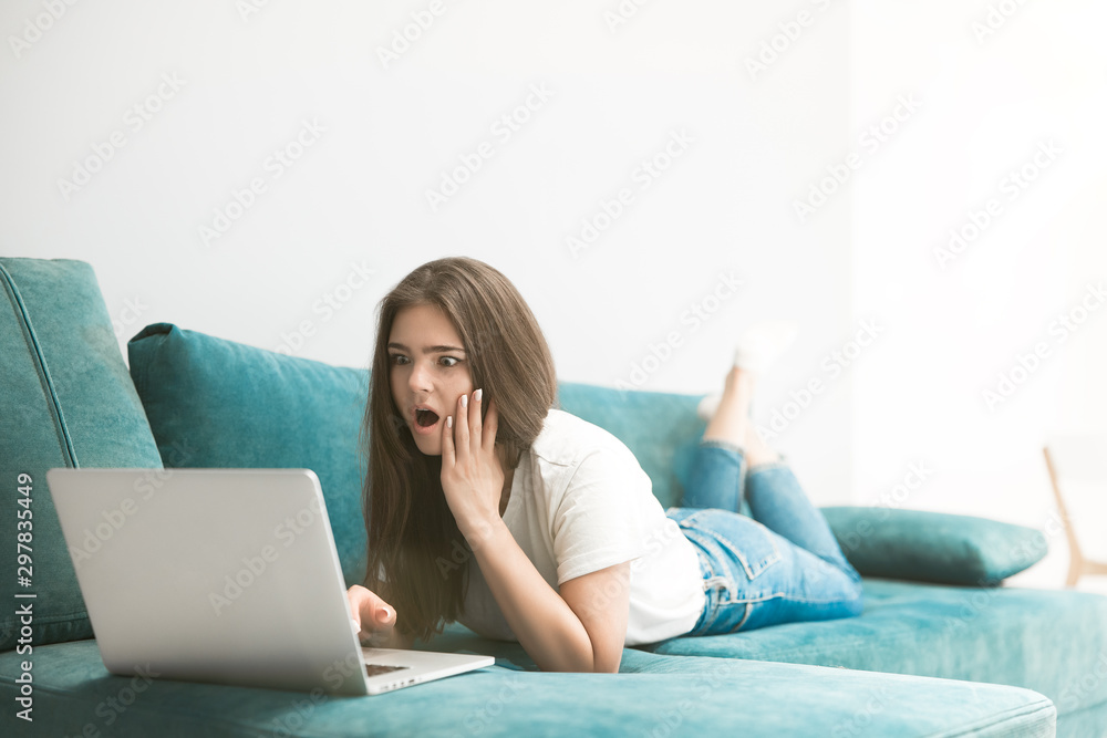 beautiful young woman watching movie on her laptop lying on the sofa beautiful young woman watching movie on her laptop lying on the sofa