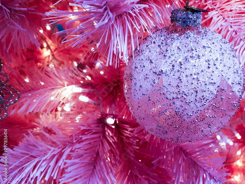 Pink Christmas ball hanging on Christmas tree. Christmas decoration. Christmas winter background. Christmas, New Year concept. Beautiful winter scene with pink New Year tree. 