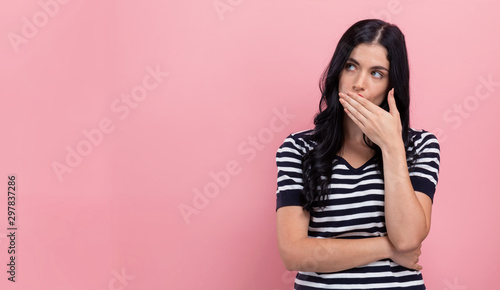 Fotografie Young woman covering her mouth on a pink background