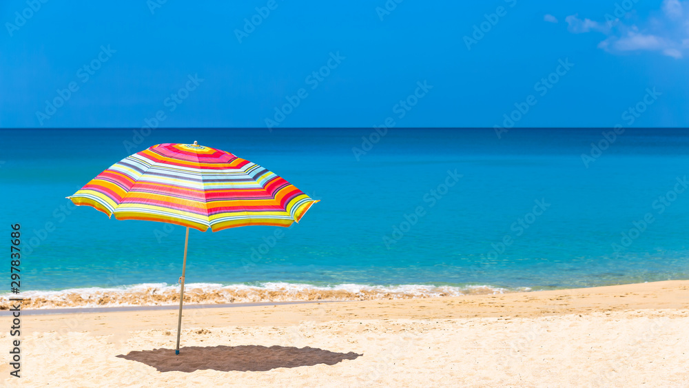 Pair of sun loungers and a beach umbrella on a deserted beach, Beach umbrella on a sunny day, sea in background. Pair of sun loungers and a beach umbrella on a deserted beach, Beach umbrella on a sunny day, sea in background.